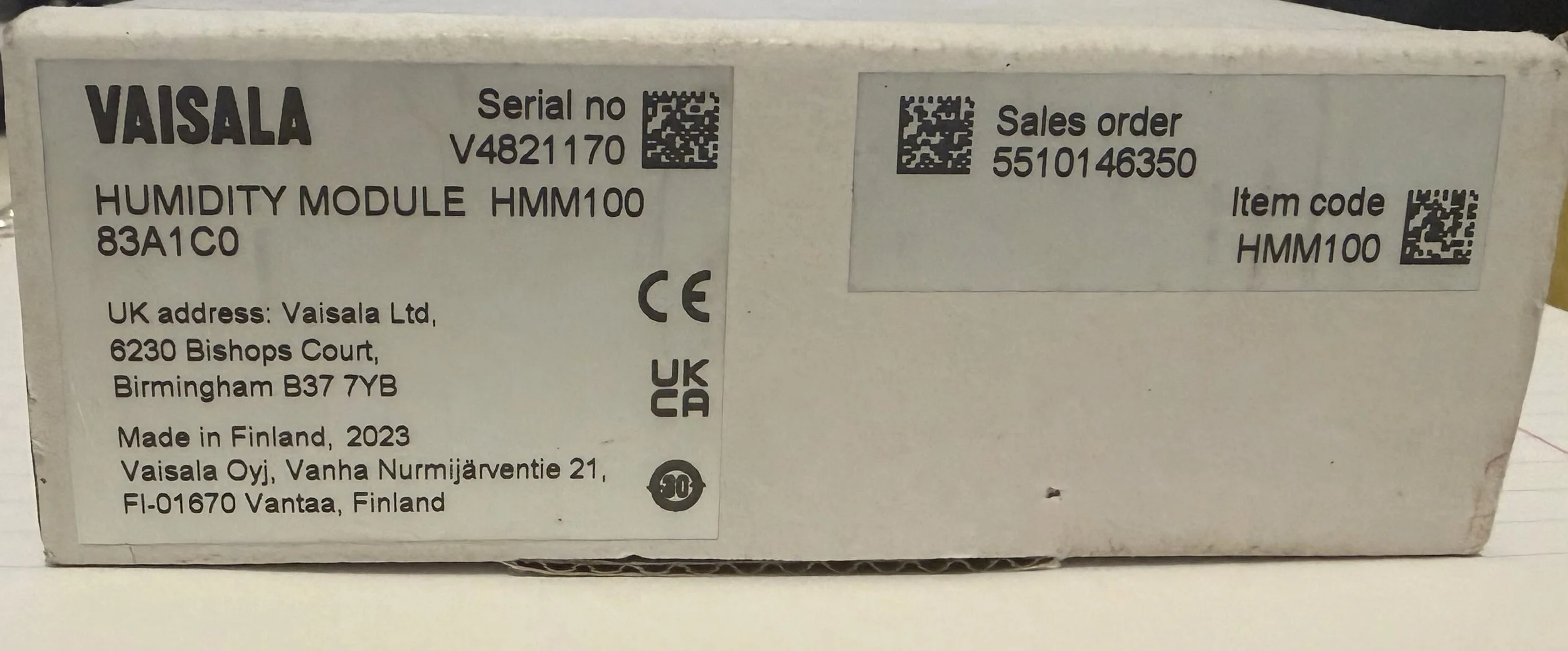 Etiqueta de un producto que indica el nombre 'VAISALA', un módulo de humedad 'HUMIDITY MODULE HMM100', con números de serie, orden de venta, código de artículo, certificaciones CE y UKCA, dirección en Finlandia y detalles de fabricación.
