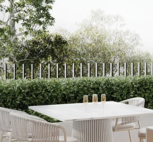 Outdoor dining table with four champagne flutes in a garden setting, surrounded by greenery and trees.