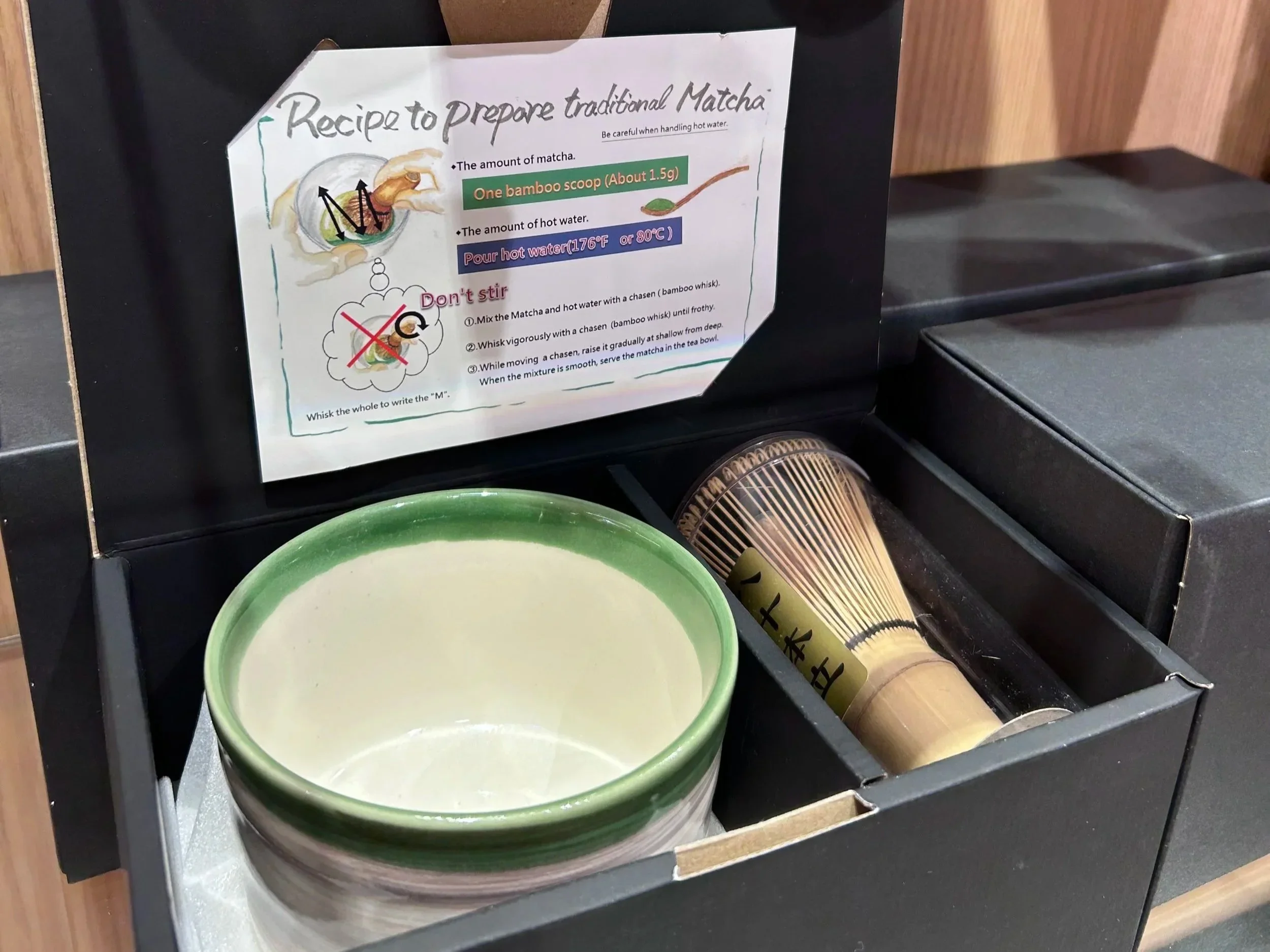 A gift set featuring a matcha bowl and a bamboo whisk in a black box.