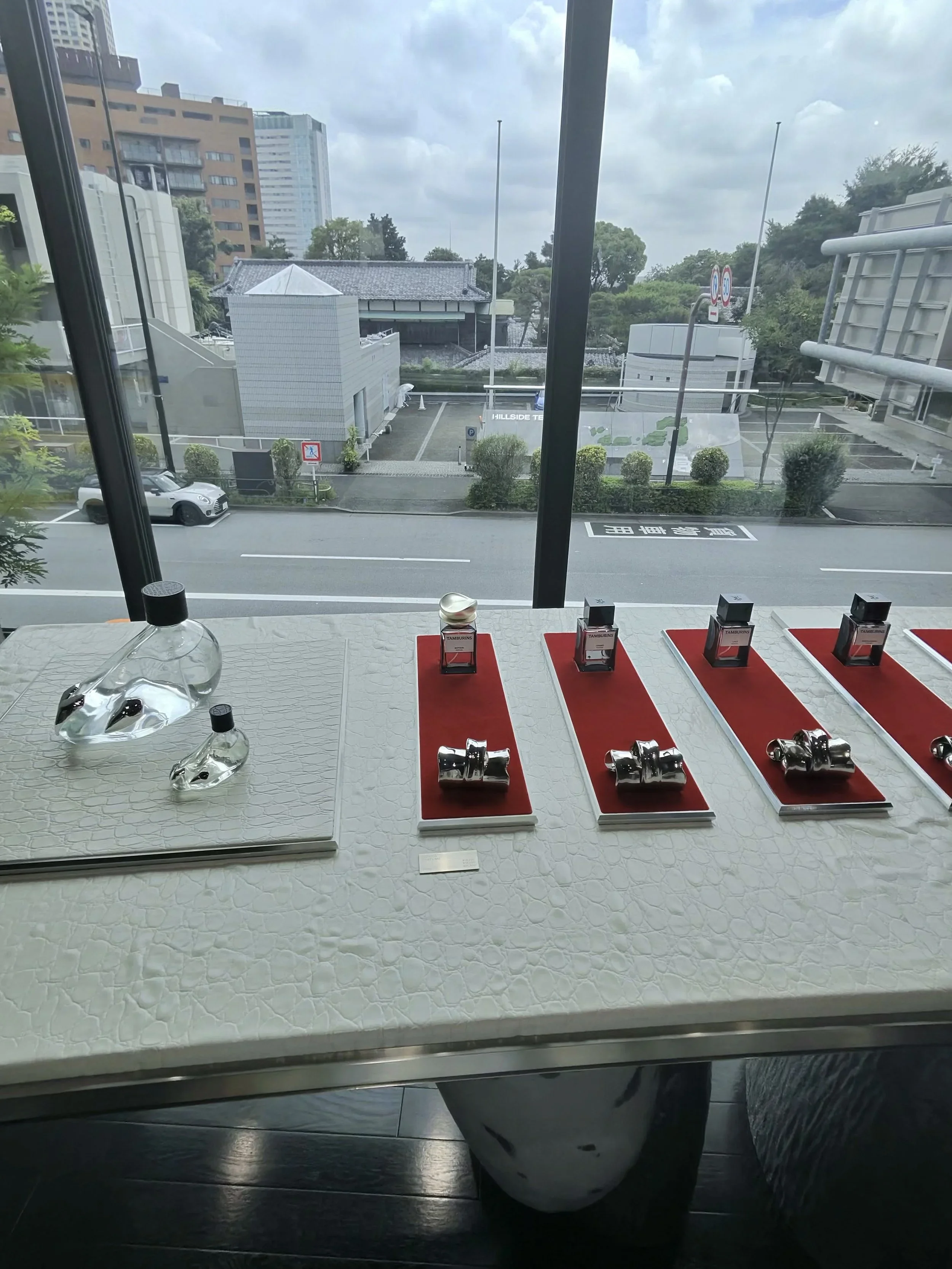 A curated fragrance display inside the Tamburins flagship store Daikanyama , showcasing the brand's minimalist packaging and artistic presentation alongside views of the surrounding neighborhood.