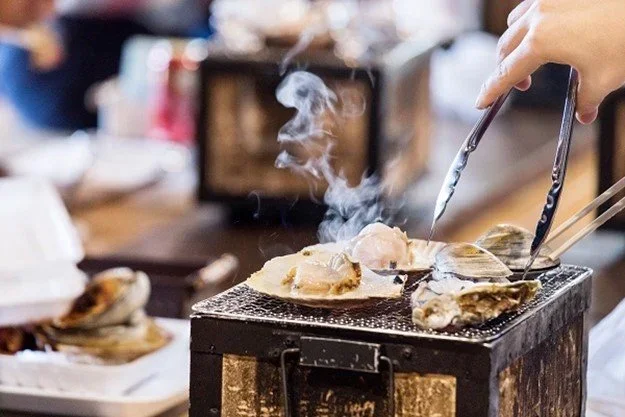 Clams being coked on a small tableside grill in Japan.