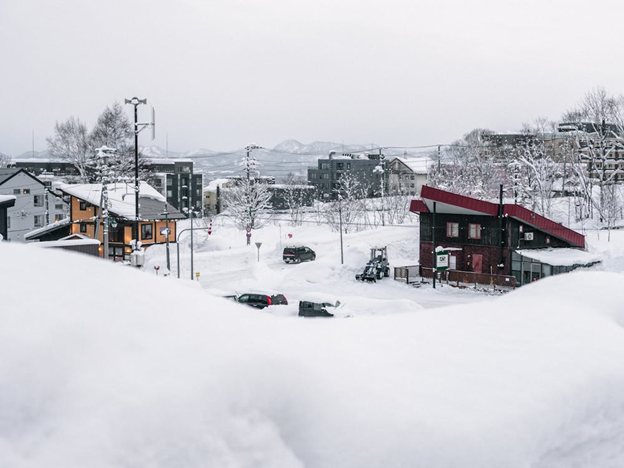 Rural Japan mountain town with independent houses and tall snowbanks.