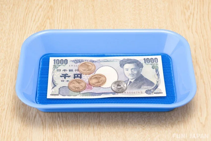 Japanese paper money and coins placed into a tray.