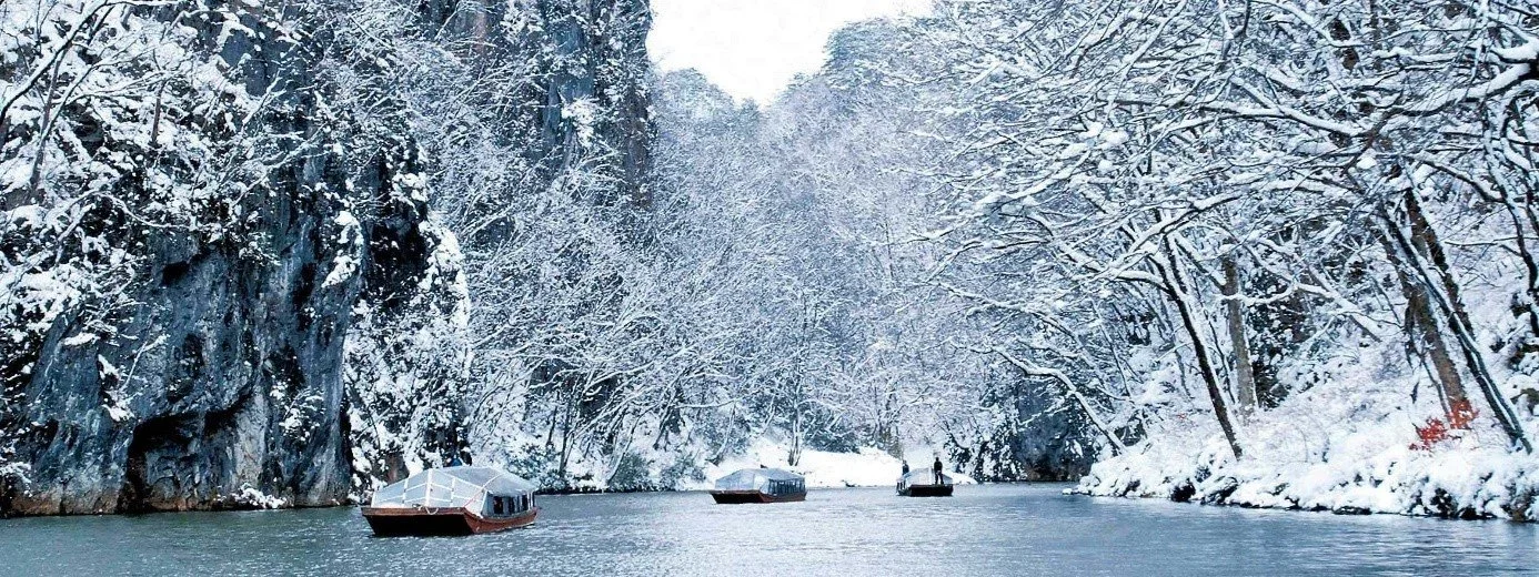 A river lined with trees covered in snow in the Geibikei Gorge in Aomori, Japan.