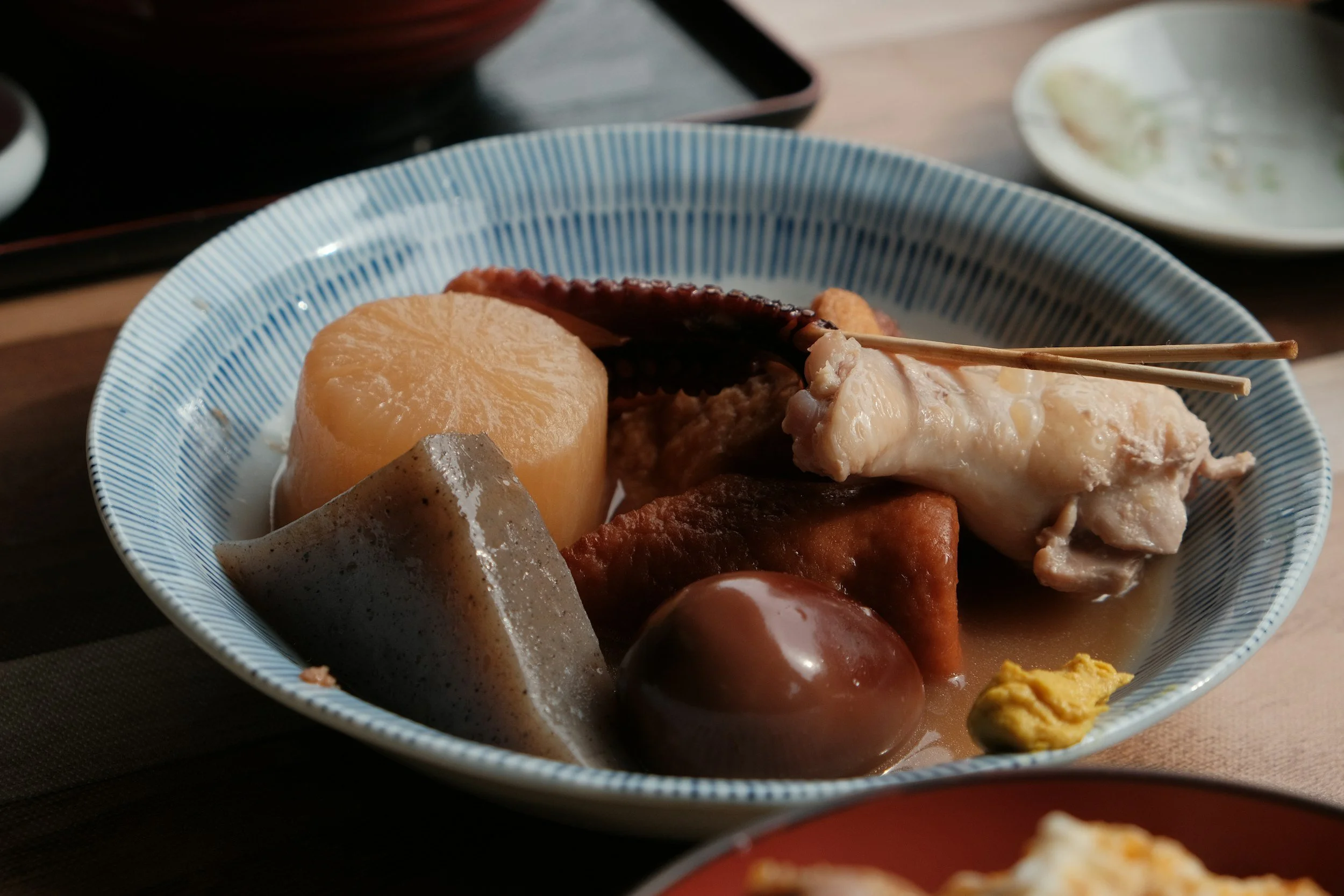 A bowl of Japanese foods including Pork, konjac, and a potato.