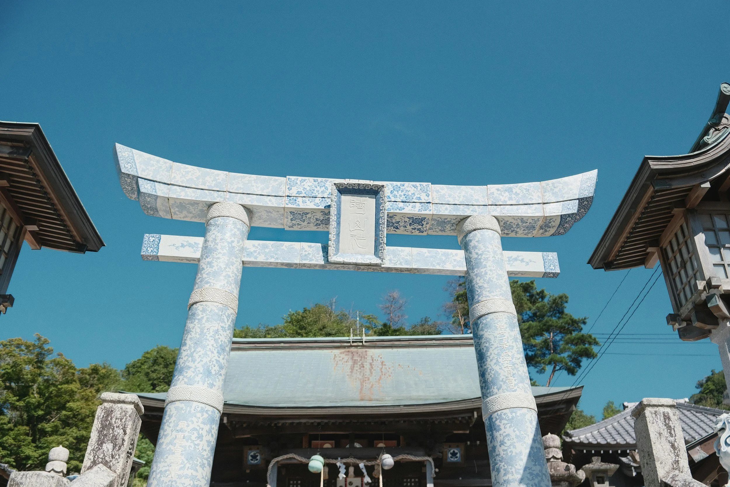 A Japanese torii arch at a shrine covered in blue and white porcelain tiles.