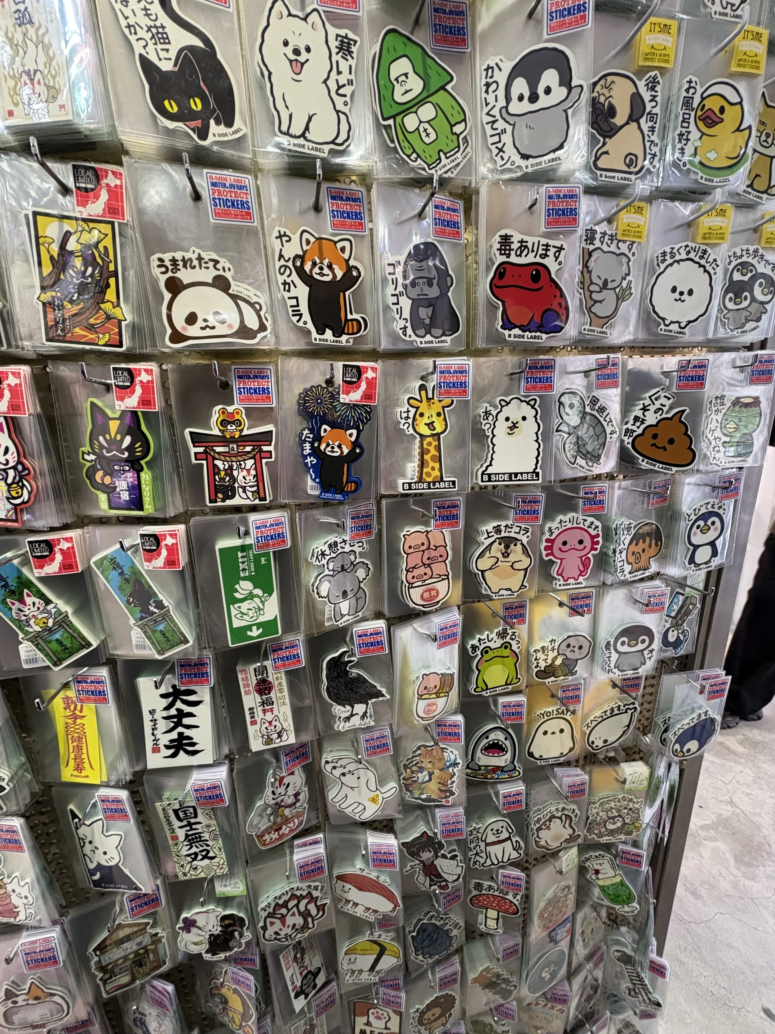 A wall of individually packaged cute Japanese cahracter stickers of animals, shrines, or various signs in Japan.