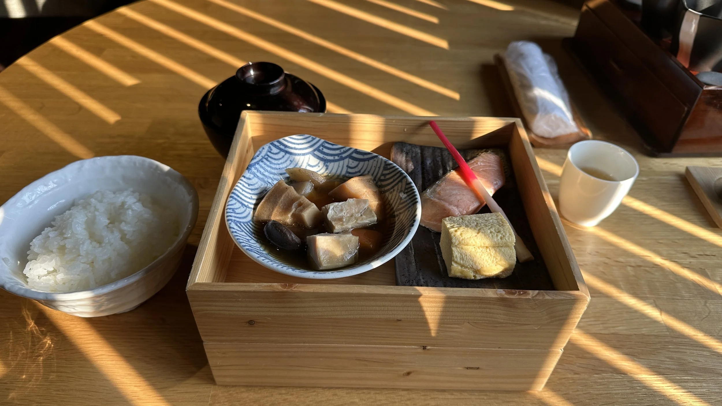 A bento box breakfast served at a Ryokan. Meal includes rice, salmon, vegetables, tamago (egg) yaki and ginger.