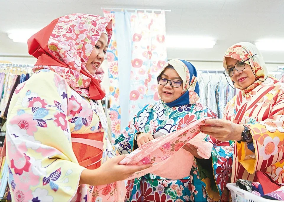 3 Ladies wearing a kimono hijab look at another floral printed hijab.
