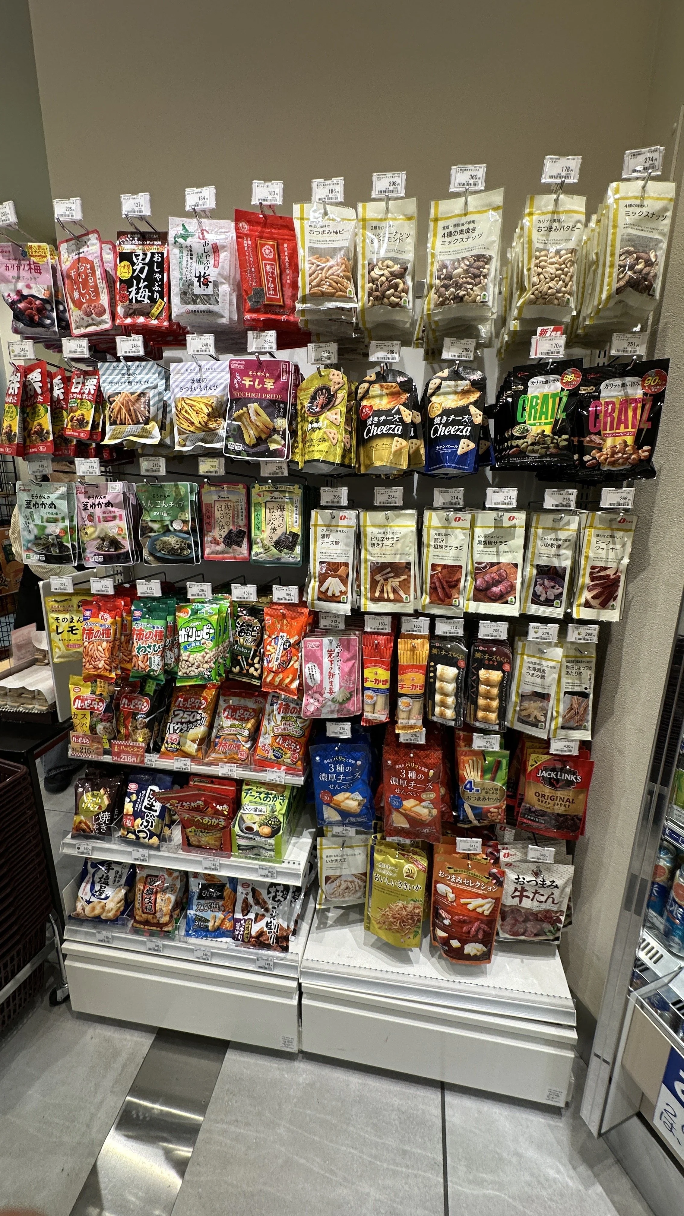 Dried foods selection at Tokyo Station Pulsta showing nuts, dried meats, and dried vegetables handing on a rack.