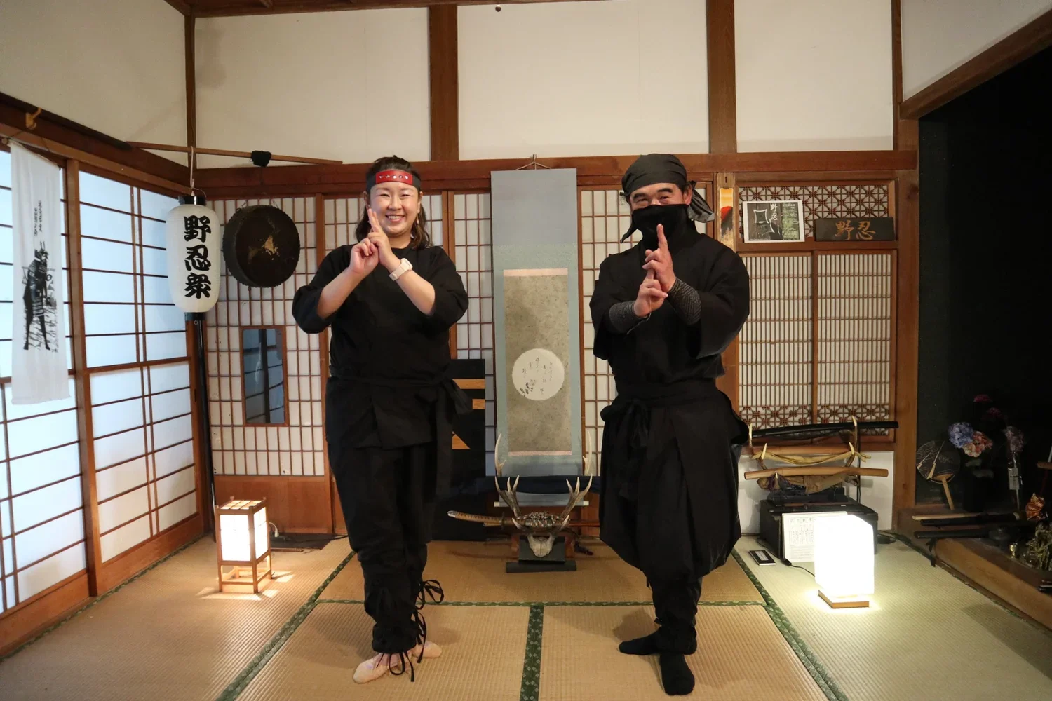 Two people stand in a tatami mat room and study the ways of the samurai.