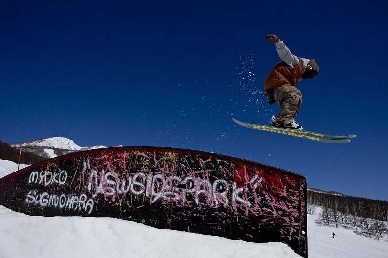 Skier jumps off element in a ski park in Myoko, Japan on a bluebird day.