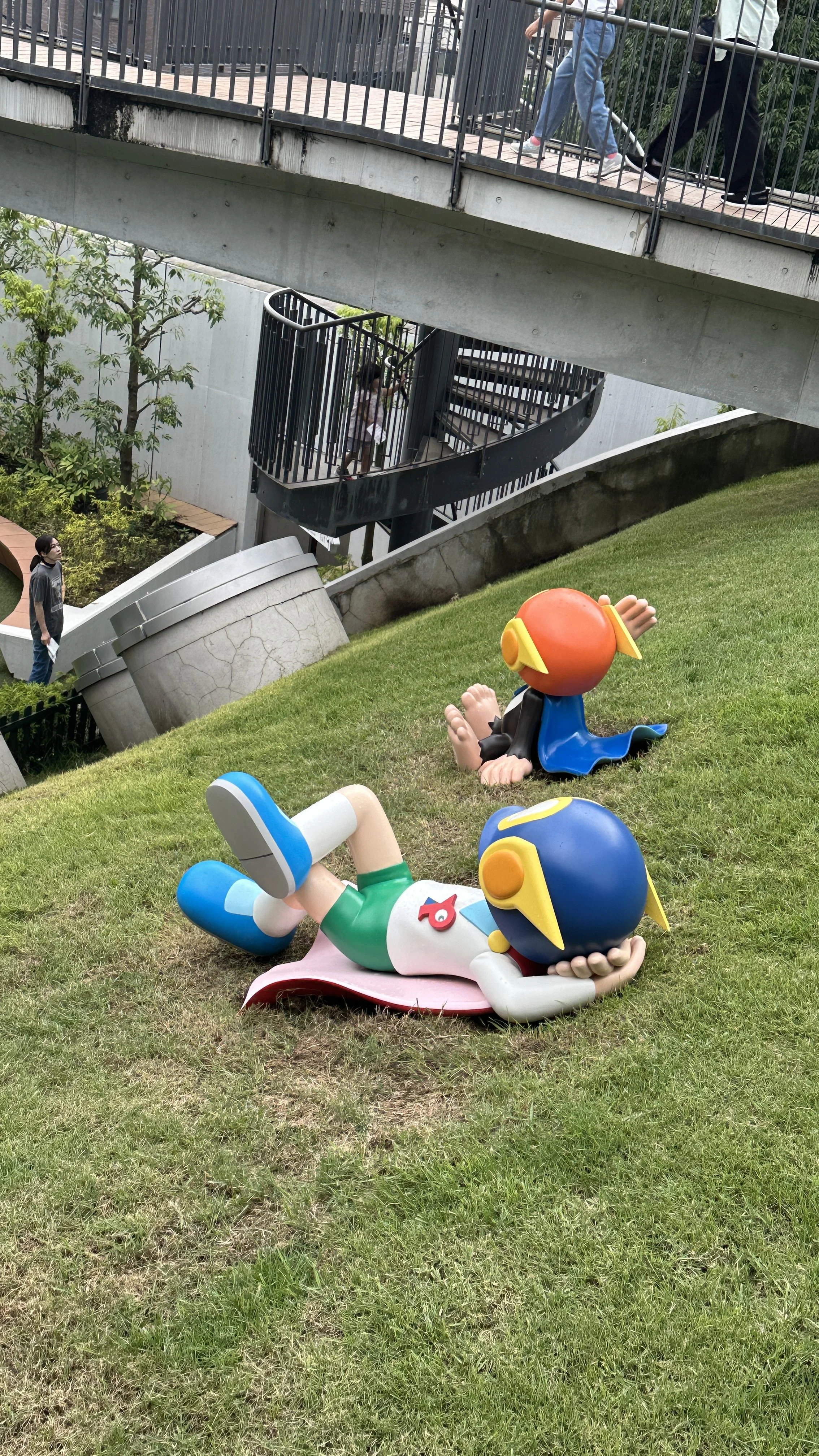 Two colorful sculptures of imaginative characters from Doremon sit on a field of grass at the  Fujiko F. Fujio museum in Kawasaki, Japan.