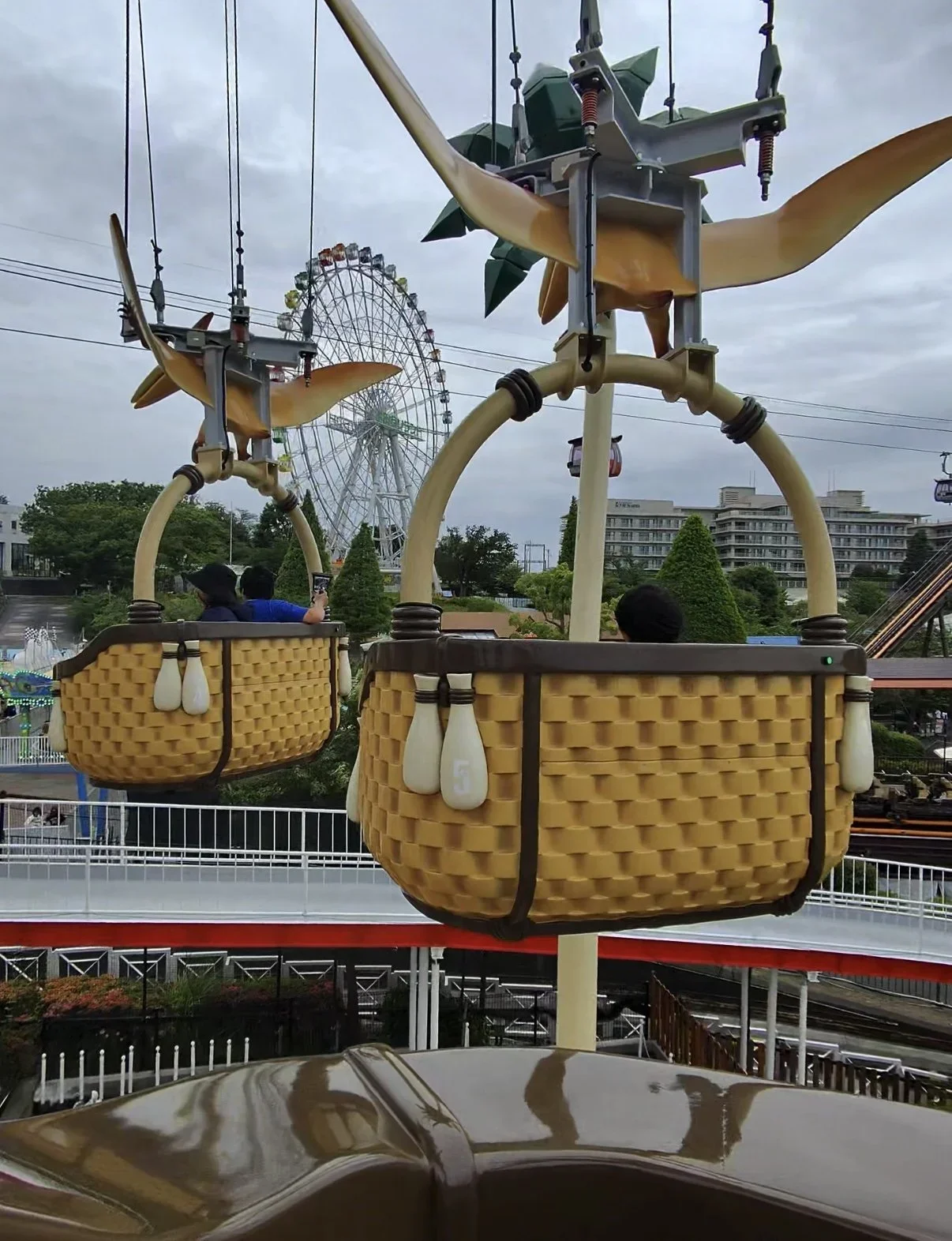 An image of a basket floating ride with a ferris wheel in the background.