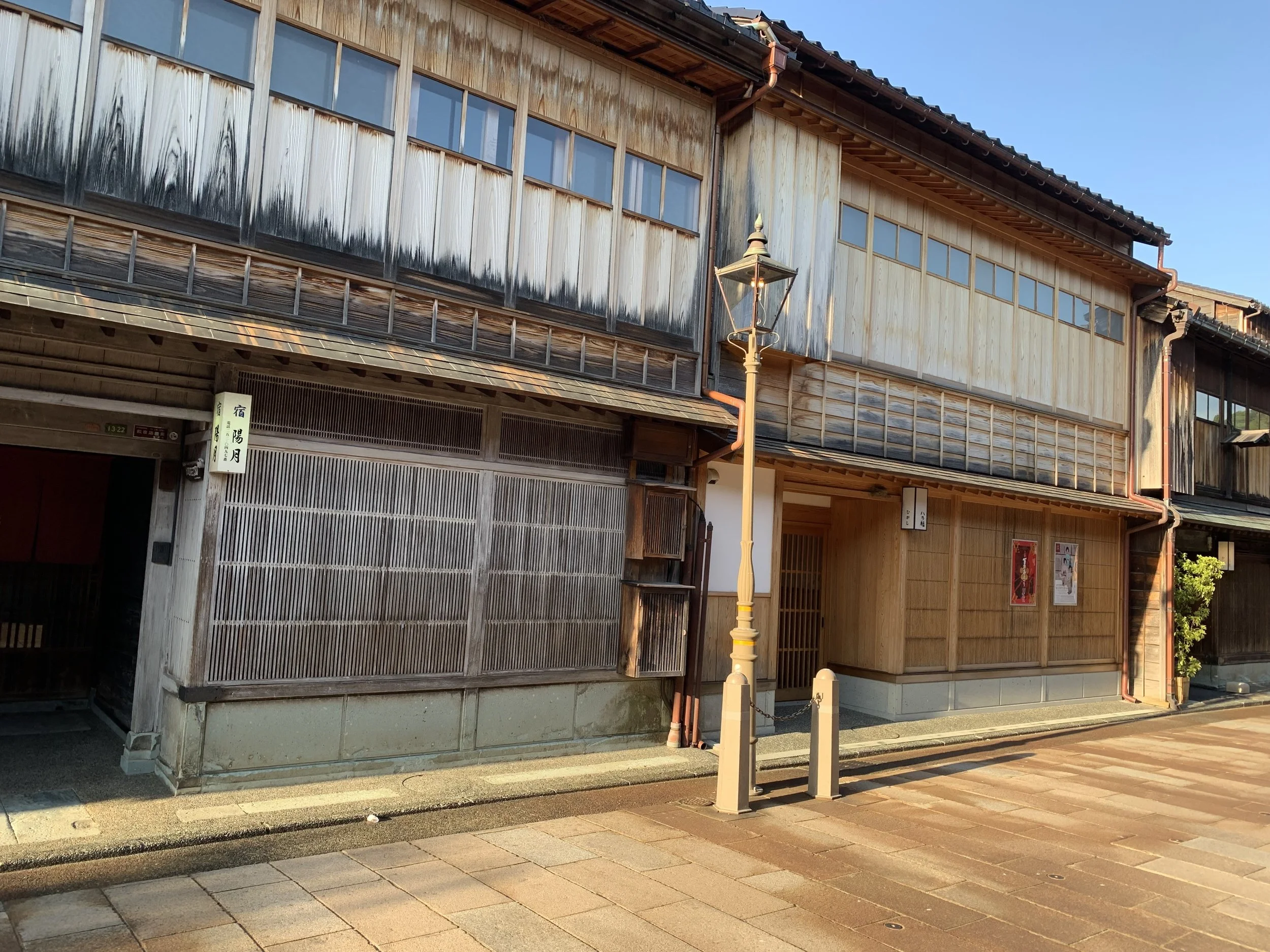 Front of an old wooden 2-story building in one of the samurai districts of kanazawa taken in the day light with a lamp post in the front.