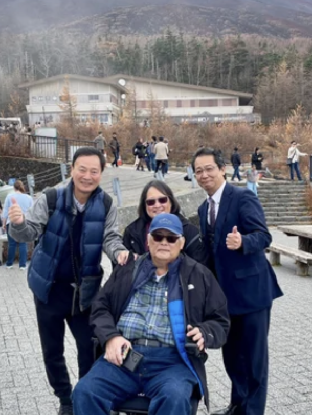 TokudAw driver wearing a suit poses with 3 guests one of which is seated in a wheelchair.