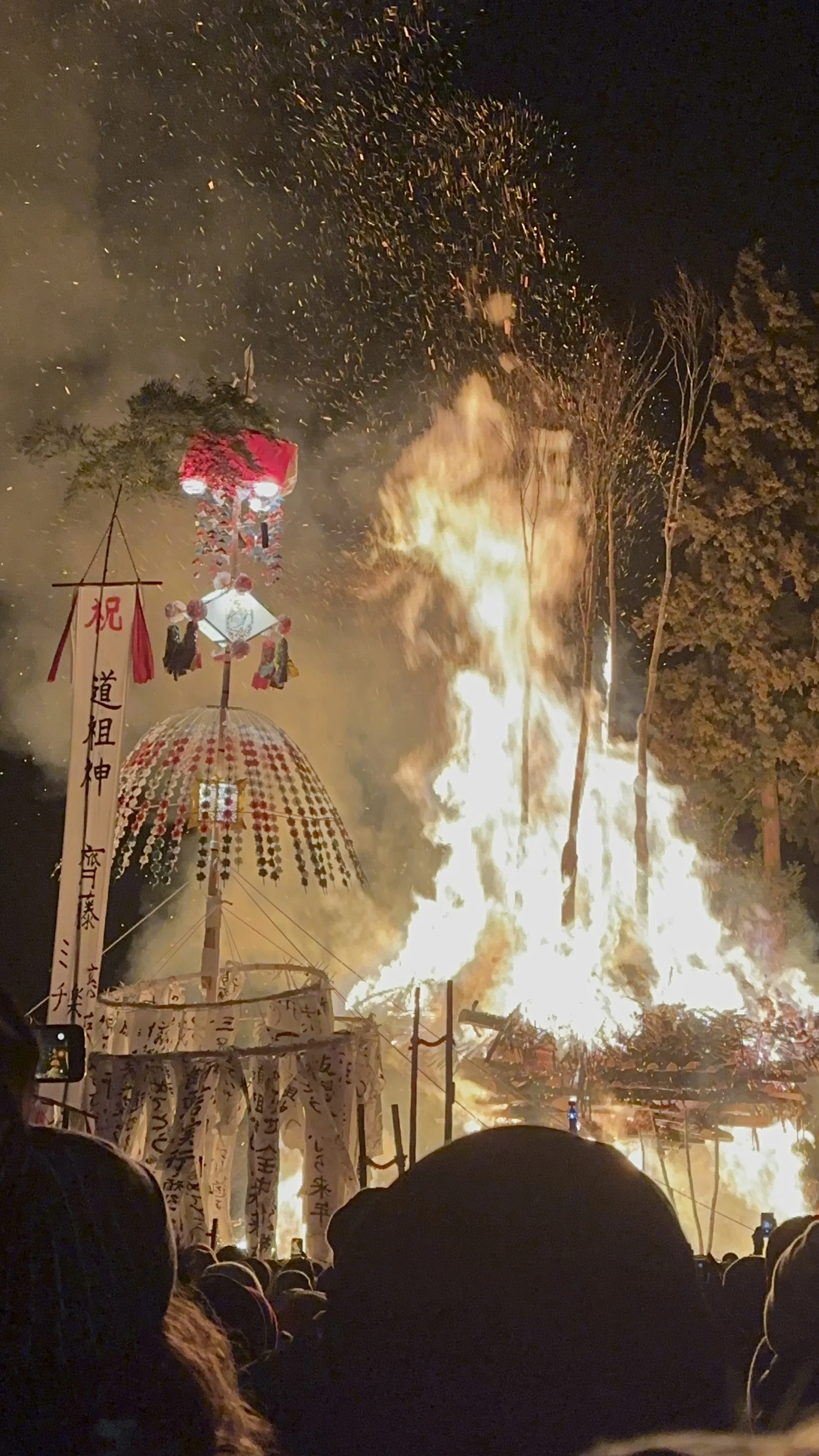 Nozawa firefestical blazes with a tall traditional Japanese bamboo and paper structure standing as tall as the fire adorned with paper wishes for the community's children.