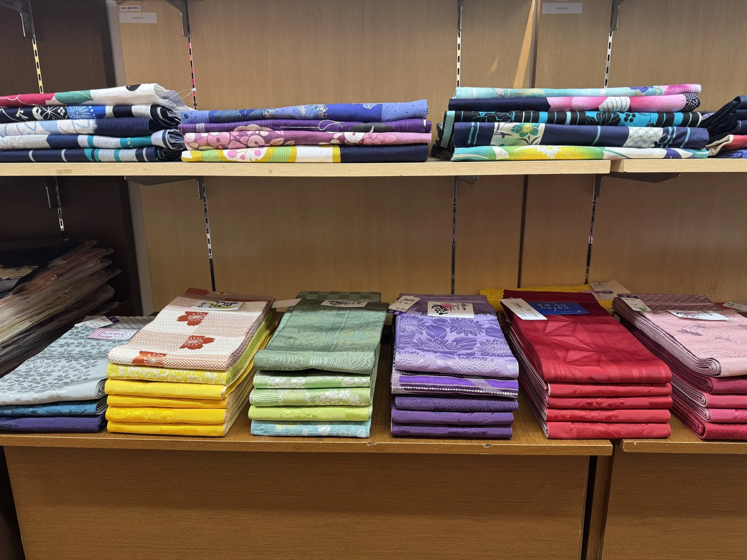 Colorful, yellow, green, purple and red obis stacked on a self inside a kimono store in Japan.