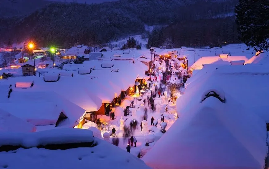 A traditional Japanese village nestled among the mountains with a warm glow of evening lights.