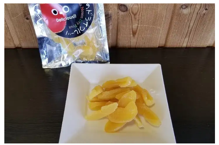 Dried apple slices on top of a white square plate with the foil bag packaging in the background.