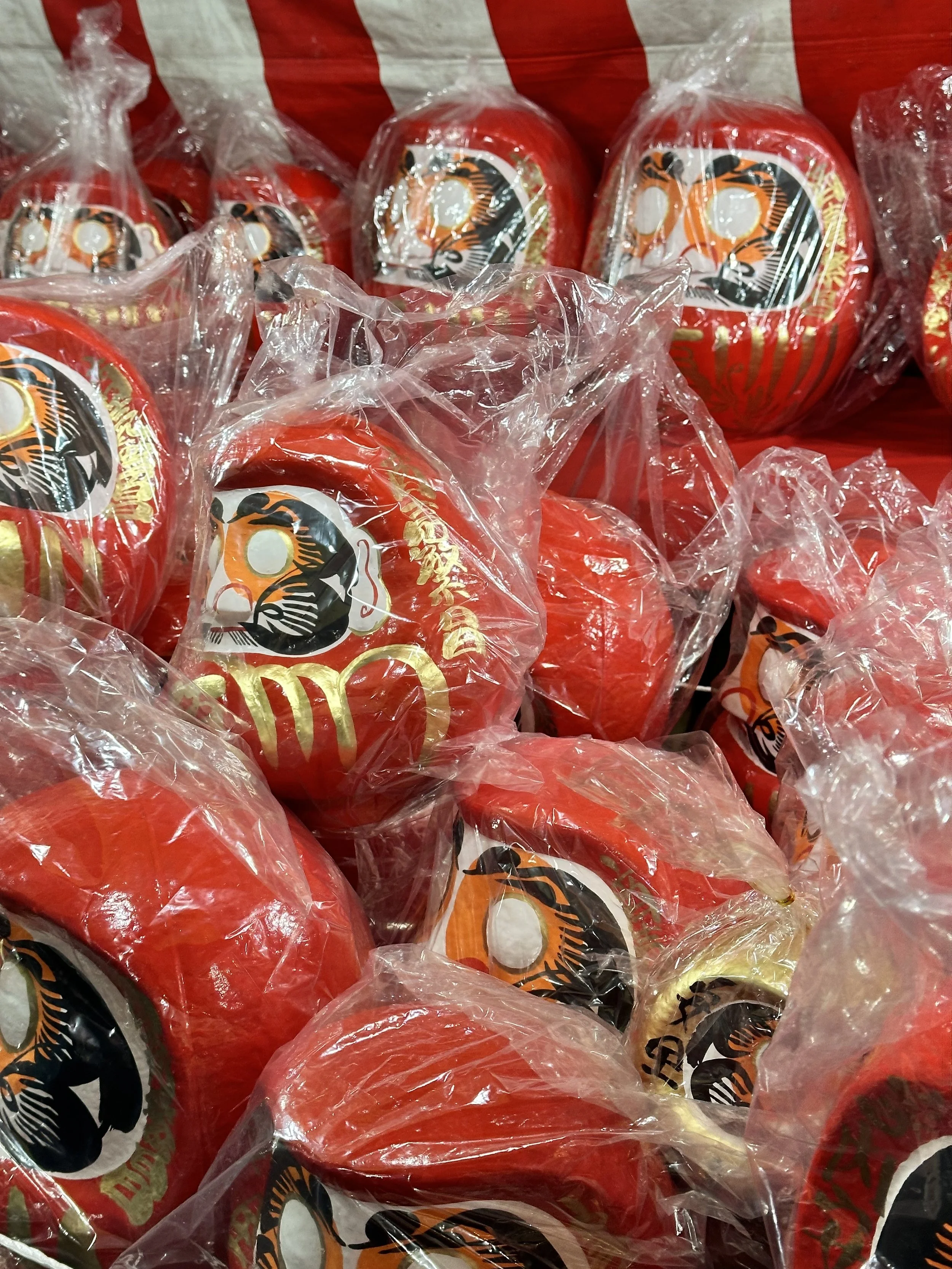 A pile of individually wrapped new daruma dolls await for their possible owner to fill in the two eyes