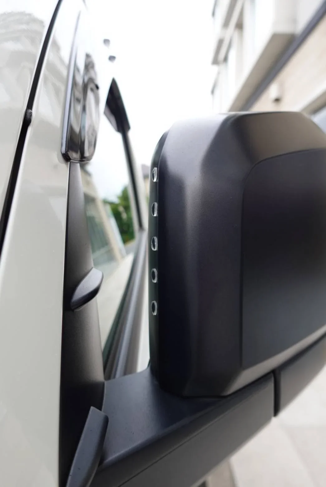 Up close image of the back of the driver mirror on the outside of a TokidAw Japan Private Driver Fleet vehicle..