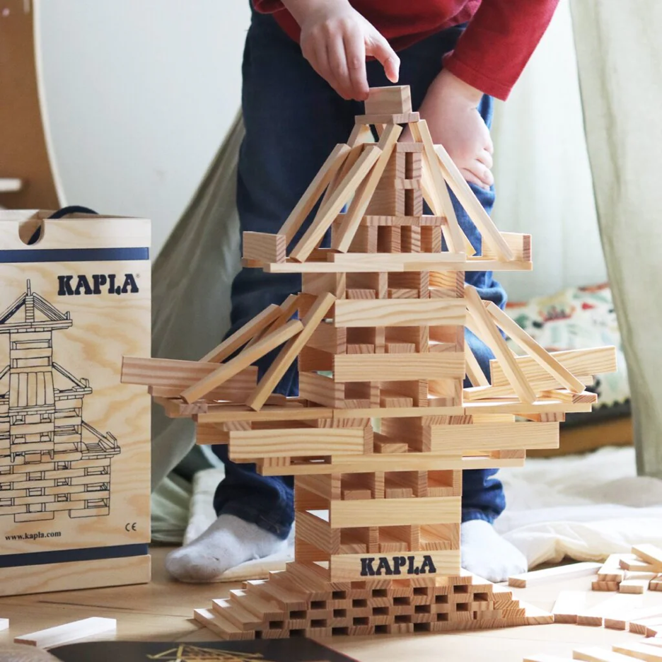 A person builds a multi-story block building with Kapla blocks, a Japanese toy.