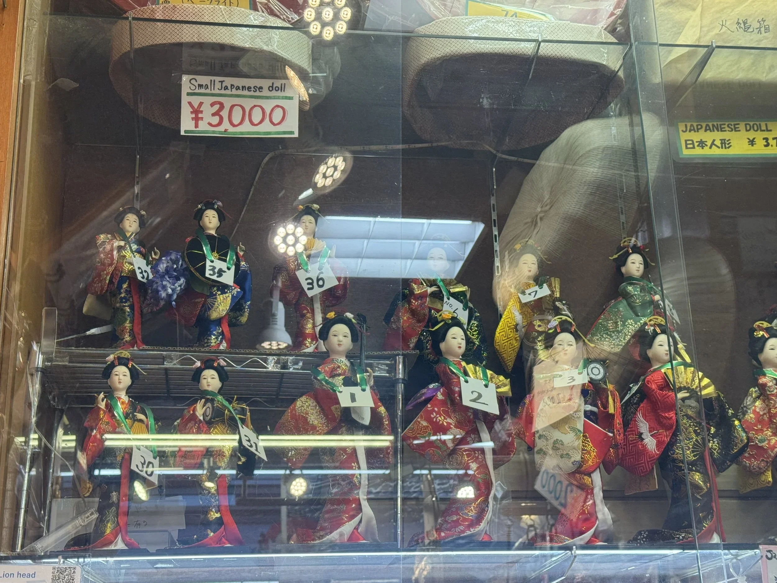 Japanese dolls wearing a kimono in a window.