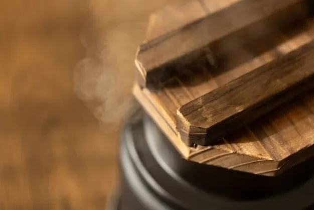 A close up of a cooking pot with a wooden lid steams.