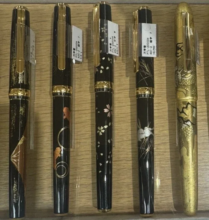 Several luxury lacquer and gold pens are lined up next to eachother.