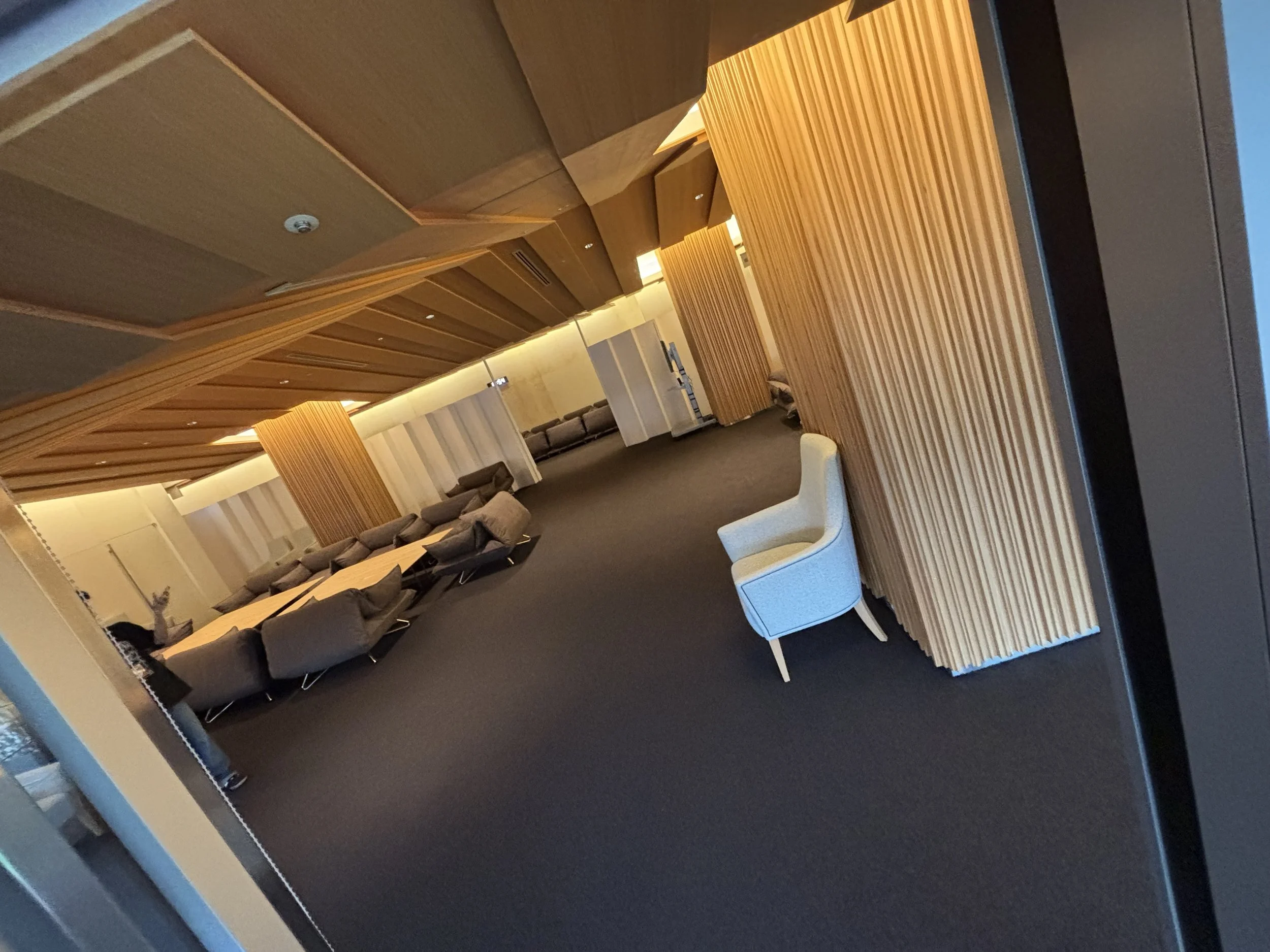 A wooden paneled, warmly lit meeting room resembles the warm woods of a tea house and is filled with tables and cushioned chairs.