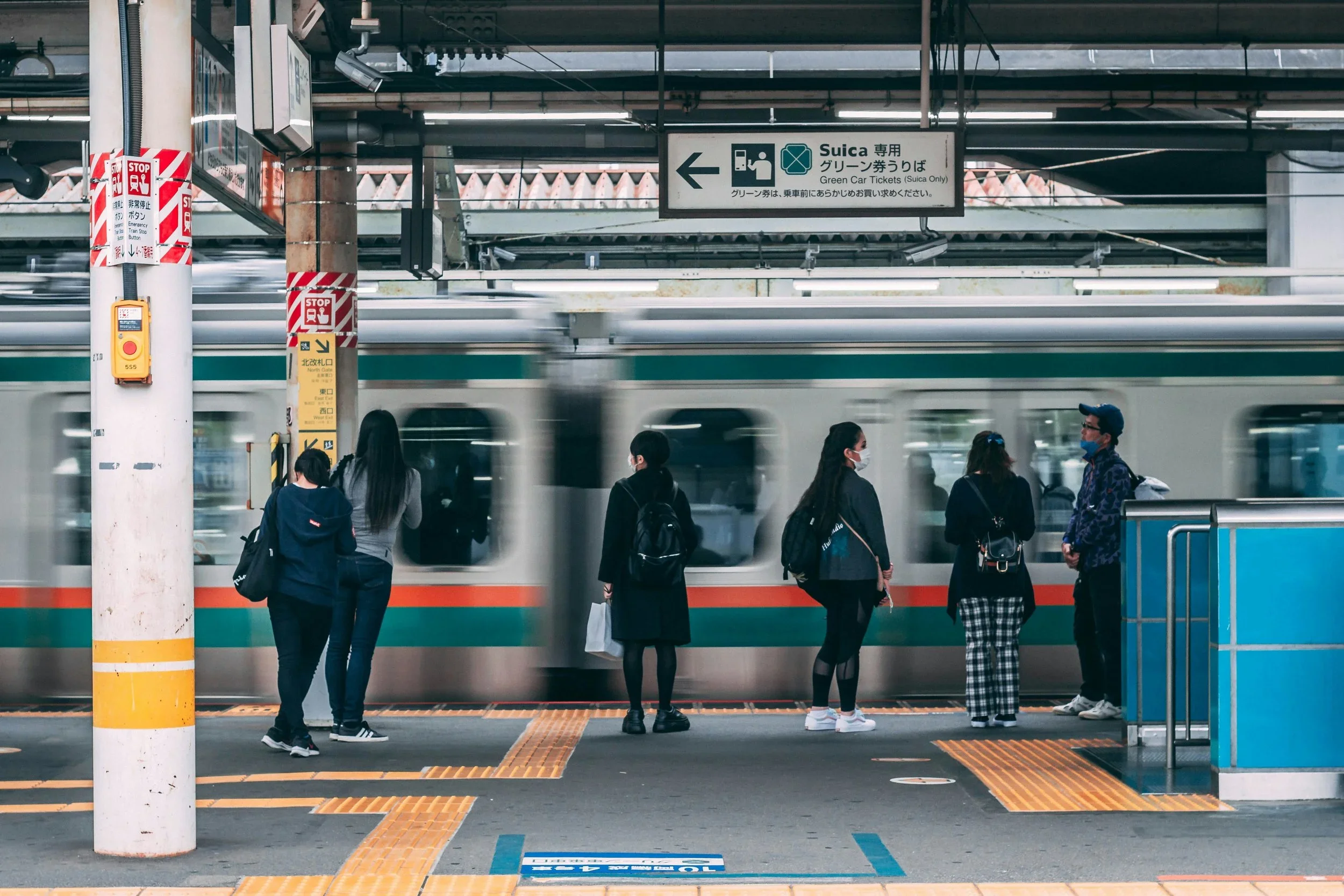 Commuters wait for a train at a Tokyo station, highlighting the clean layouts, clear wayfinding, and efficient public transportation design that shape everyday life in Japan.
