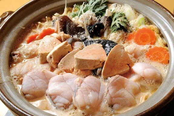 A vegetable hot pot with a creamy broth simmers in a pot.