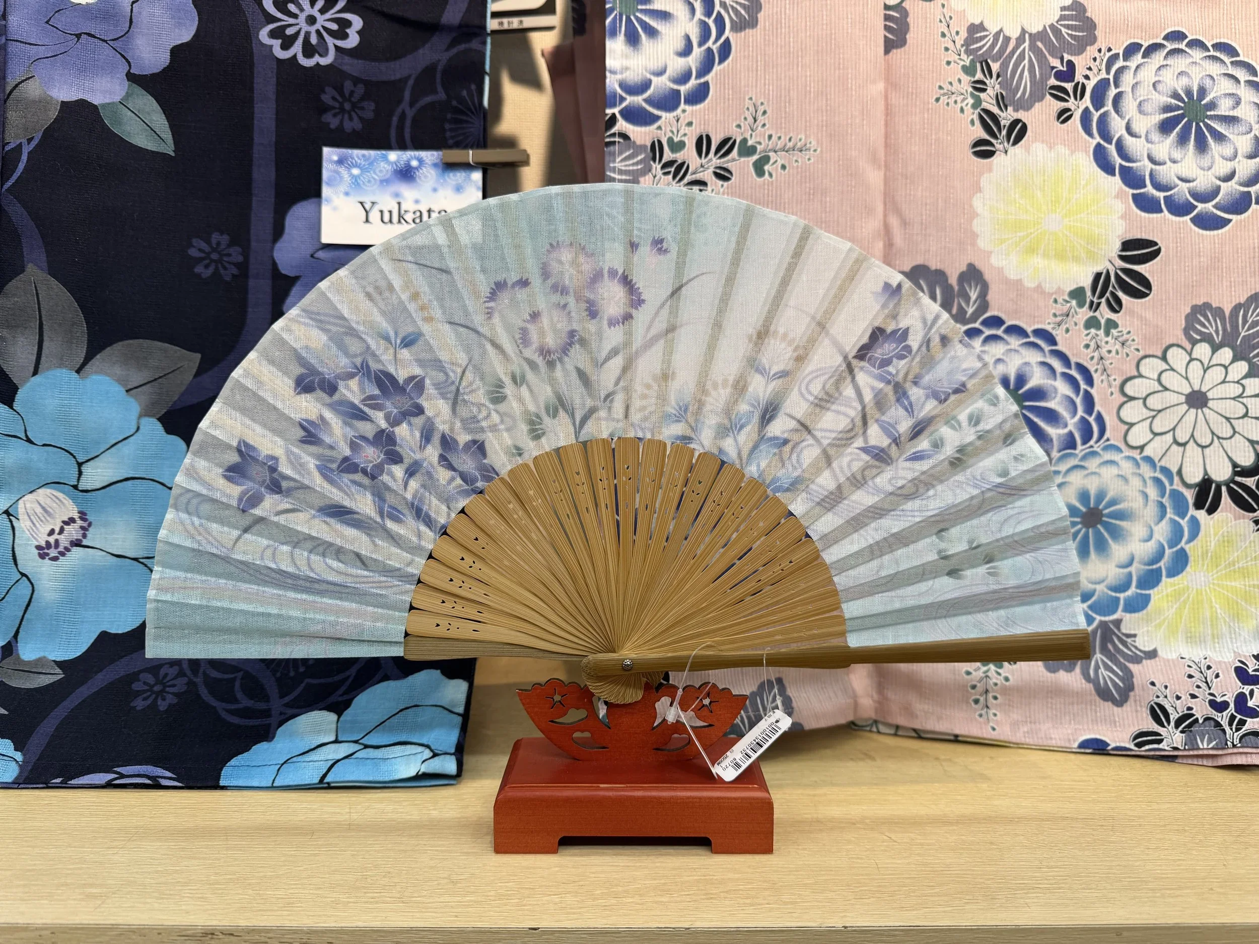 A floral blue and purple Japanese fan on display at a kimono store.
