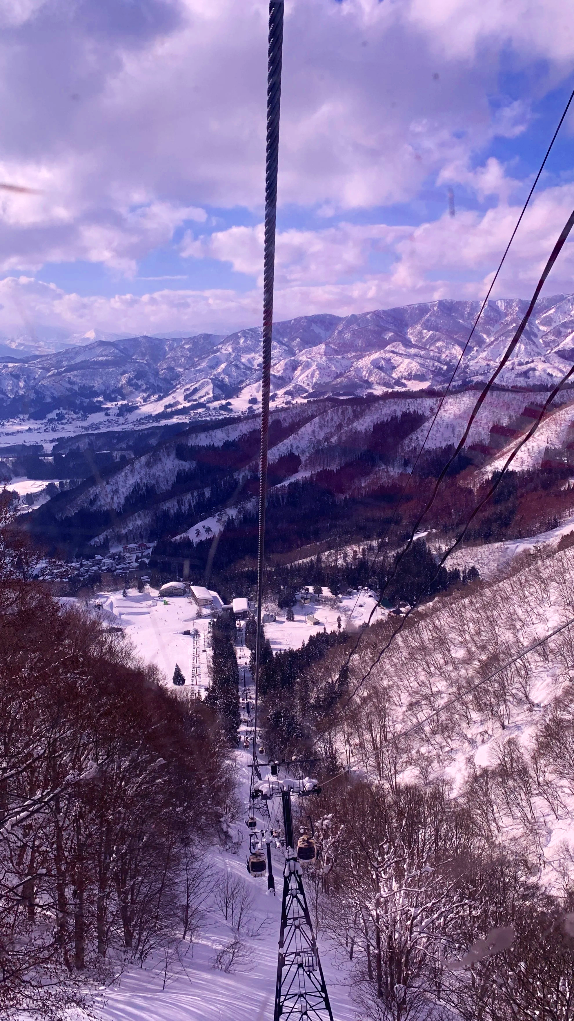 A purple tinted view of Nozawa valley take from one of the goldola windows looking down over the snow covered valley.