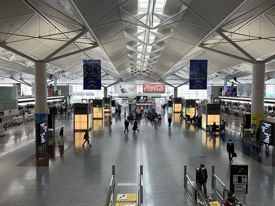 Chubu International airport, original source from Wikipedia, used with attribution under Creative Commons. Image is of the interior hallway of the departure terminal at check-in taken from above looking down at people walking along the corridor.