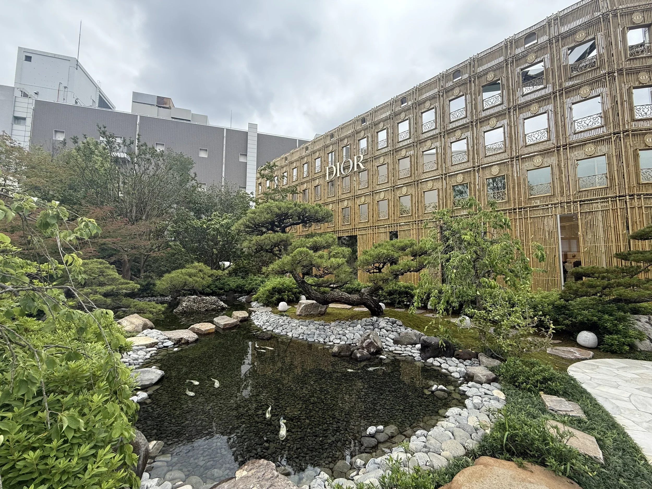 The landscaped garden outside the Dior Shibuya flagship store blends traditional Japanese garden design with contemporary luxury architecture, creating a peaceful retreat in the heart of Tokyo's shopping district.