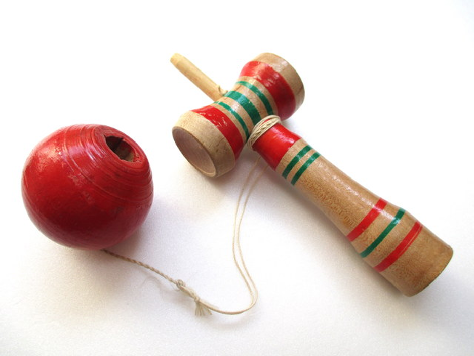A red ball attached to a red and green striped wooden mallet.