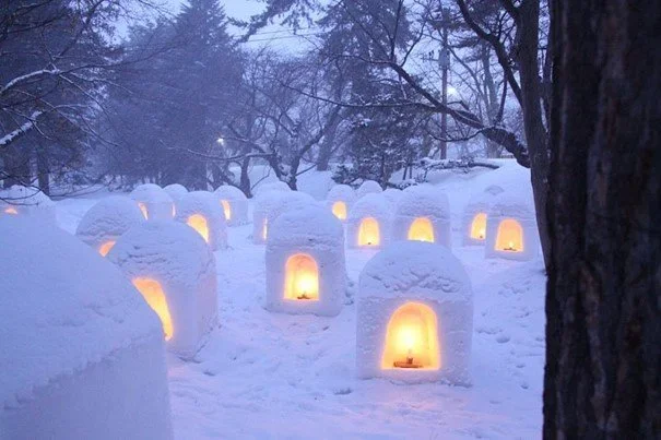 Snow lanterns in the shape of a dome across a snow covered landscape.