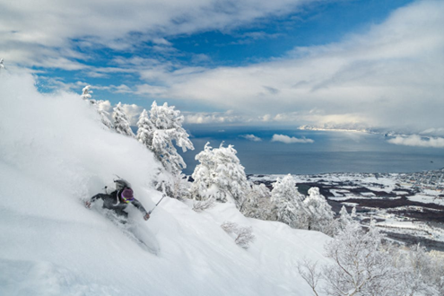 Skier bounds through the powder snow in the backcountry of Japan.