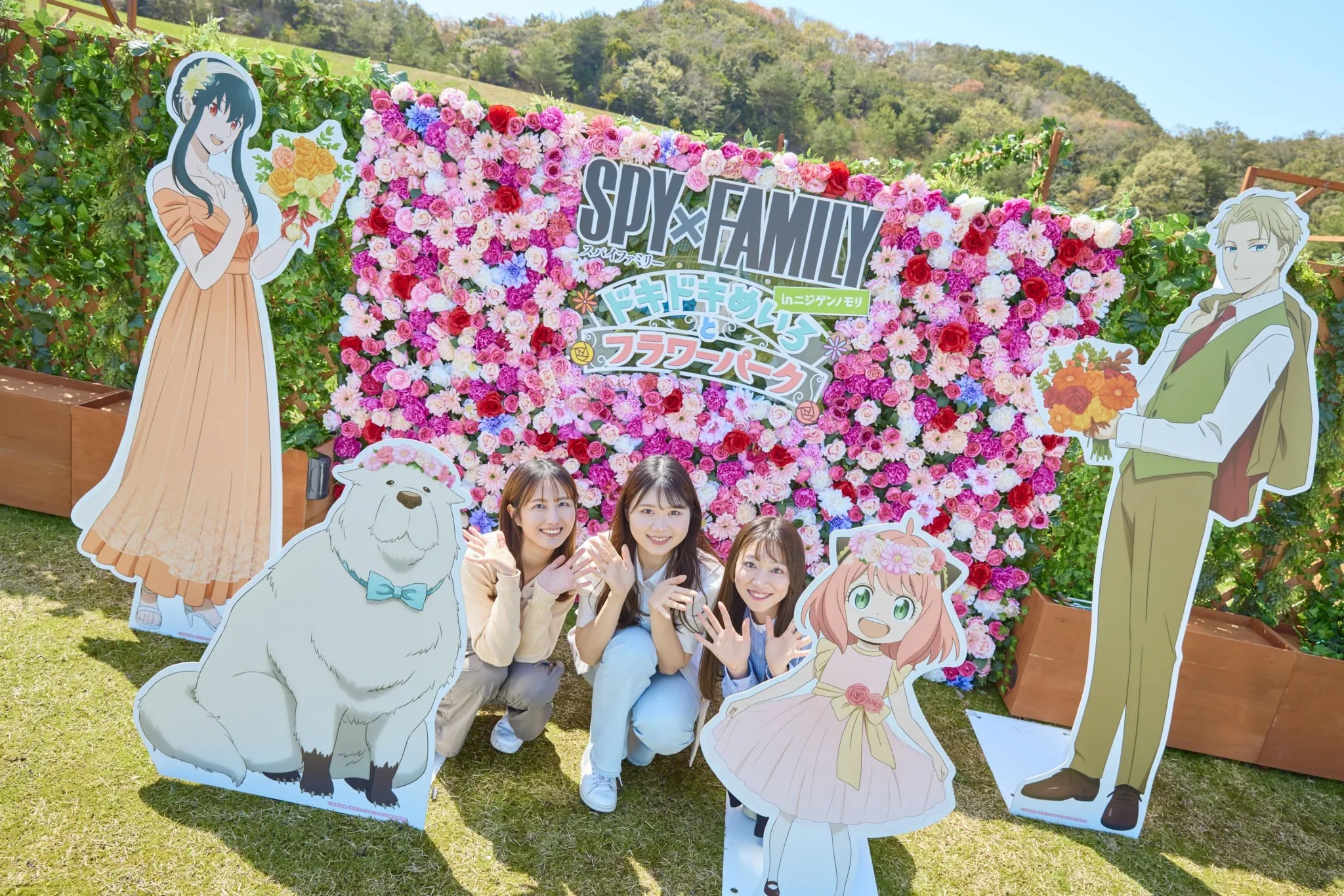 Three ladies pose in front of Spy Family cardboard cut outs.