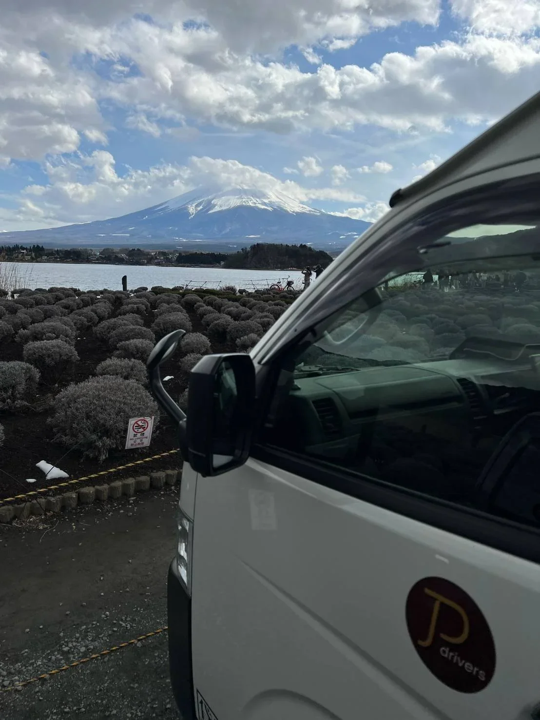 A Japan Private Driers van is parked in front of the lake at Mount Fuji on a cloudy  and sunnyday.
