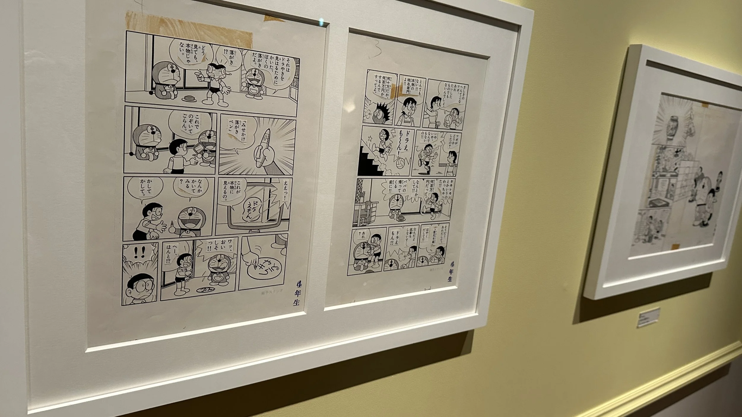 Hand drawn sells of the cartoon Doraemon mounted to a wall in a white frame.