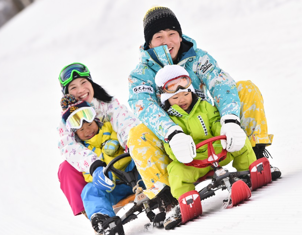 family sledding down a snowy hill smilling
