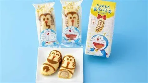 A Doreamon and Tokyo Banana collaboration that shows 2 items on a white square plate with 3 packaged pieces behind it.