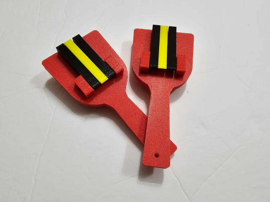 Red, black, and yellow wooden spatula-like clappers.