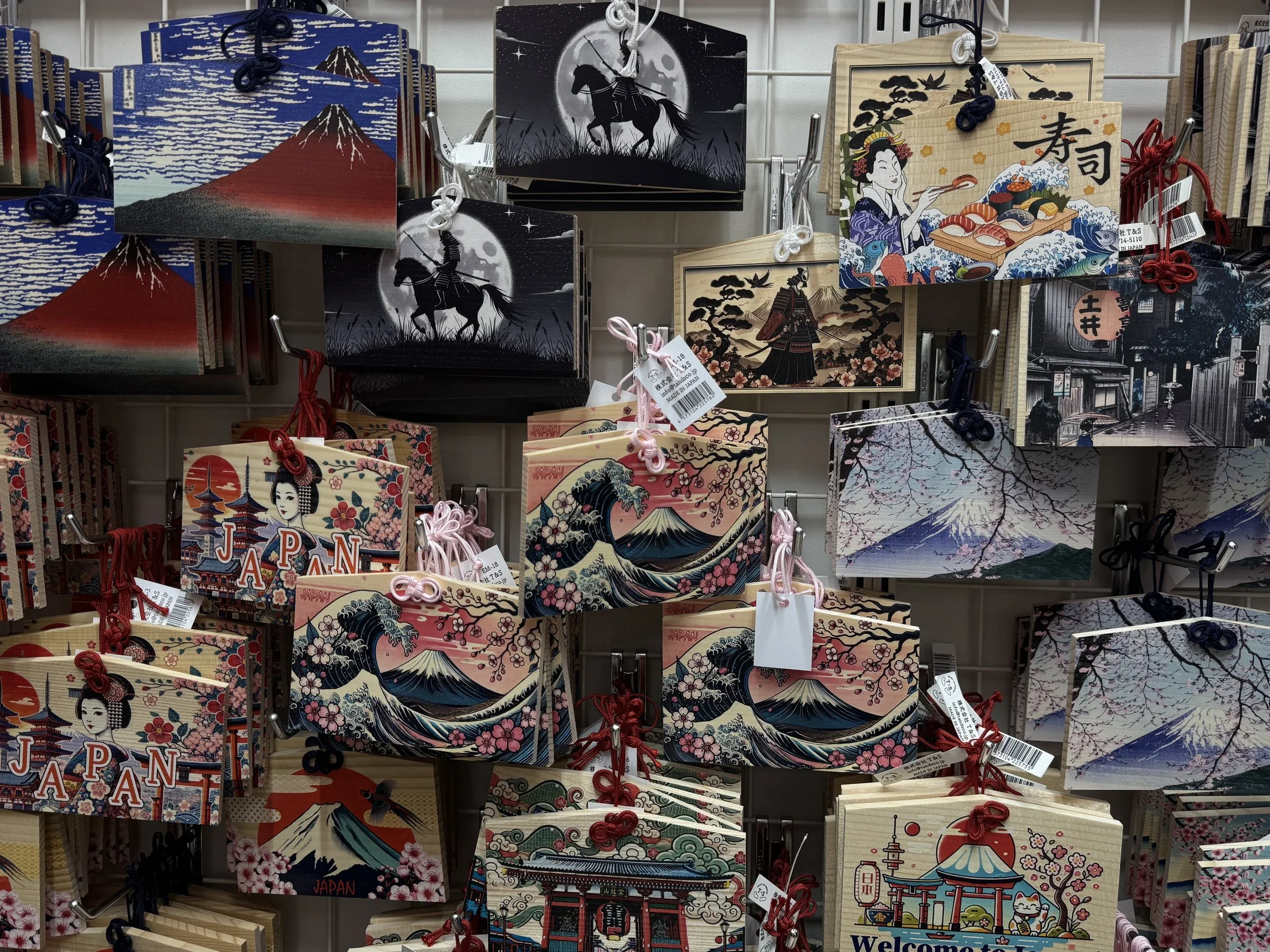 Wooden prayer planks called Ema decorated with Japanese motifs such as the great wave, sushi, Mt Fuji and ninjas.