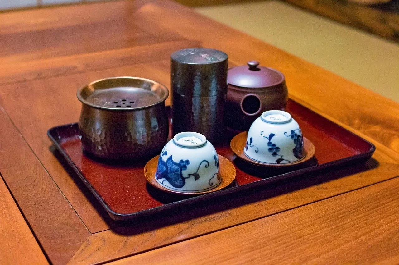 A Japanese tea set featuring two blue and white floral decorated cups and, a teapot, a matcha holder and a tray for the items.