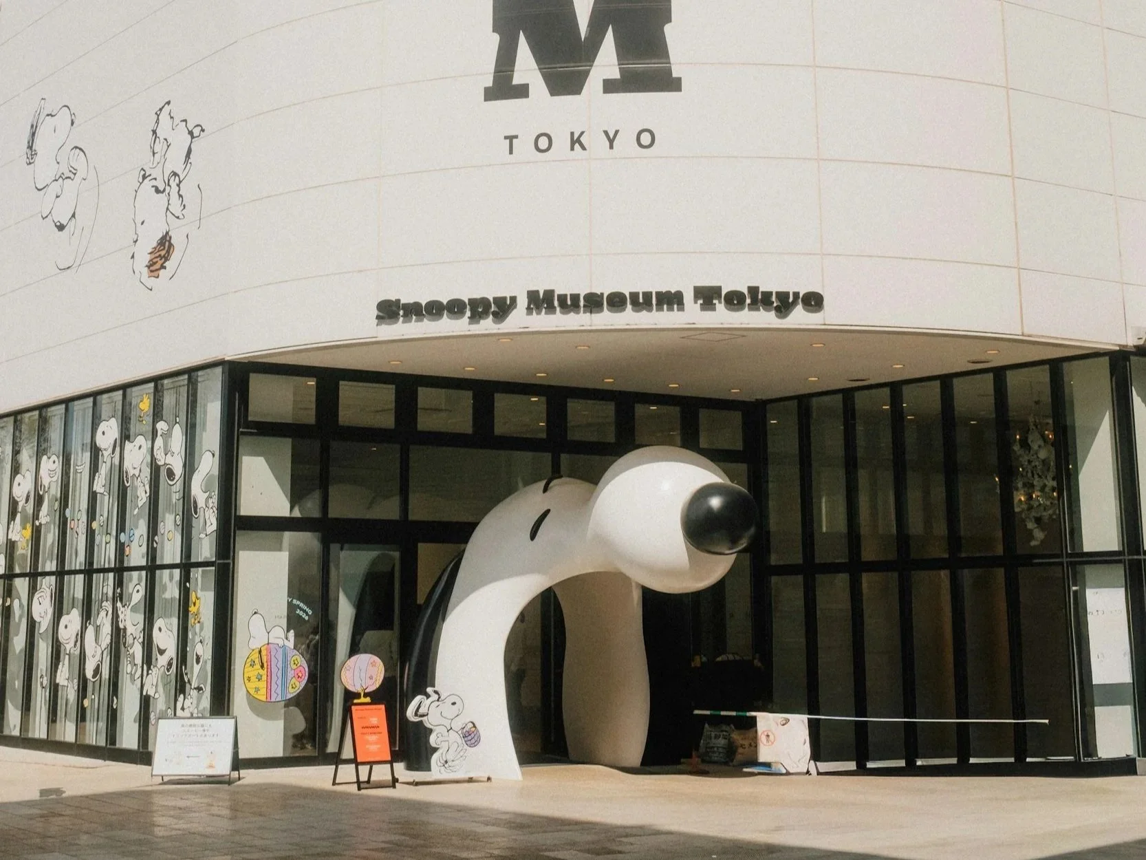 The entrance of the snoopy museum and a sculpture of Snoopy with his mouth open as a sculpture one must walk through to enter the building.