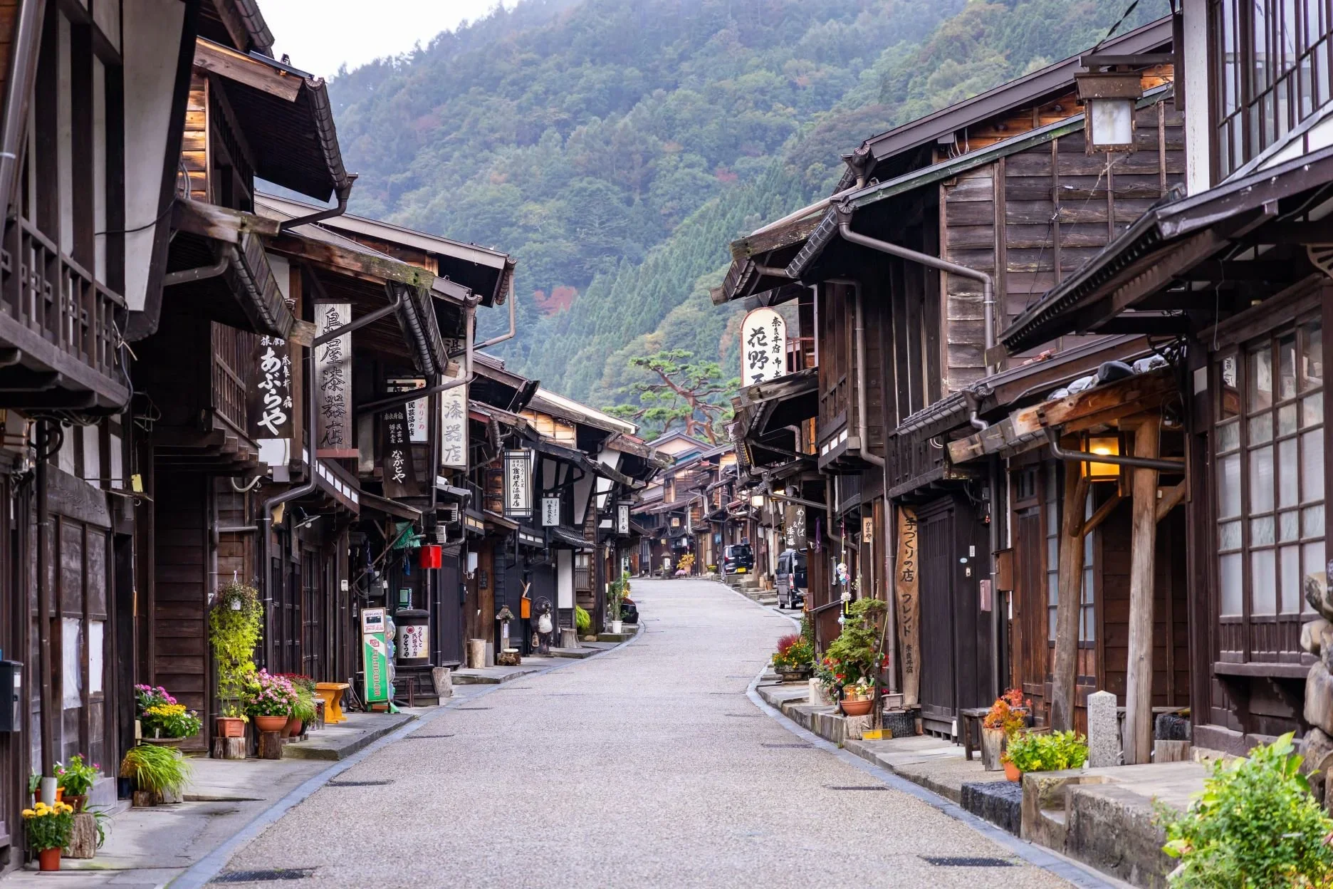 A traditional Japanese post town with a narrow street and wooden archtiecture.